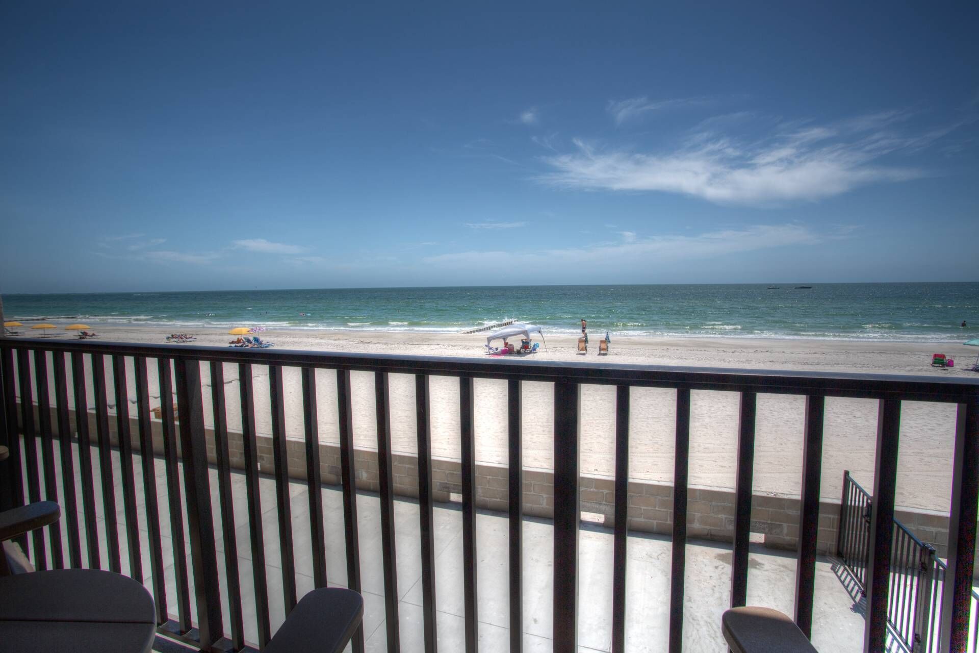 Une vue sur la plage depuis un balcon doté d’une balustrade, avec une plage de sable et l’océan en toile de fond.