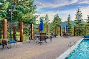 An outdoor pool area with a fence, chairs, and tables.