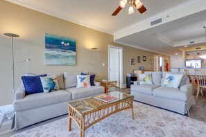 A living room with two sofas, a glass coffee table, and a painting on the wall.