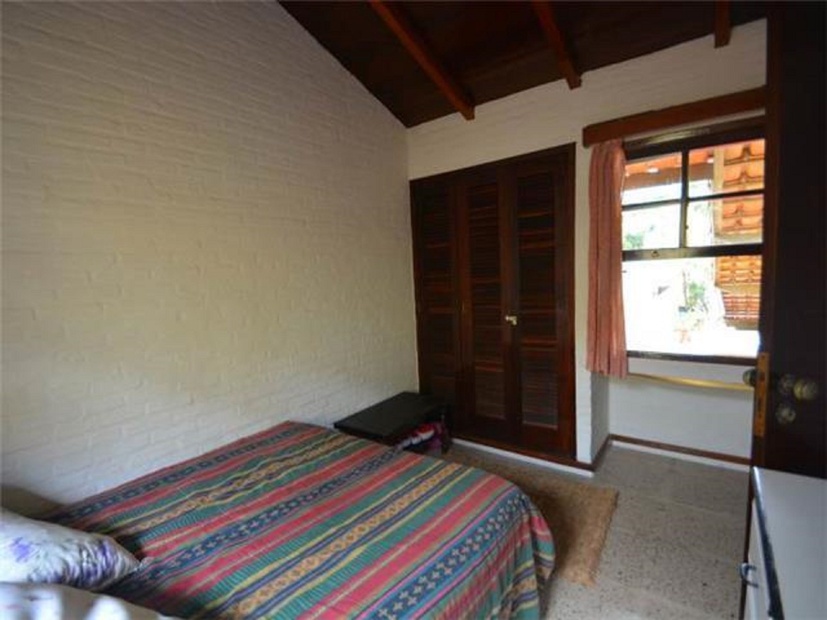 A bedroom with a bed, a wardrobe, and a window.