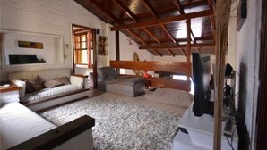 A cozy attic bedroom with a sloped ceiling, a sofa, a bed, and a TV mounted on the wall.