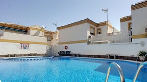 Ein Swimmingpool mit klarem, blauem Wasser, umgeben von Gebäuden mit Balkonen und einem weißen Zaun.