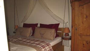 A bedroom with a bed, a wooden wardrobe, and a hanging lamp. - Ferienhaus Becker (Roedental)