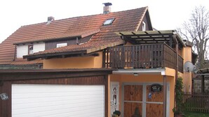 A two-story house with a garage, a balcony, and a small garden area. - Ferienhaus Becker (Roedental)