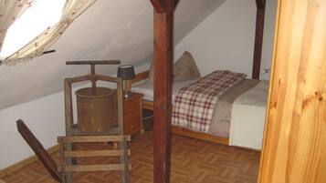 Une petite chambre mansardée, chaleureuse et accueillante, avec un lit en bois, une chaise et une table en bois.