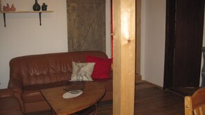 A brown leather sofa with a cushion, a wooden coffee table, and a red pillow. - Ferienhaus Becker (Roedental)