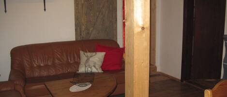 Un sofá de cuero marrón con un cojín, una mesa de centro de madera y una almohada roja.