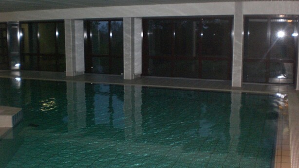 An indoor swimming pool with clear water, tiled floor, and large windows along one side. - Apartment at the harbor, Germany (Lübeck)