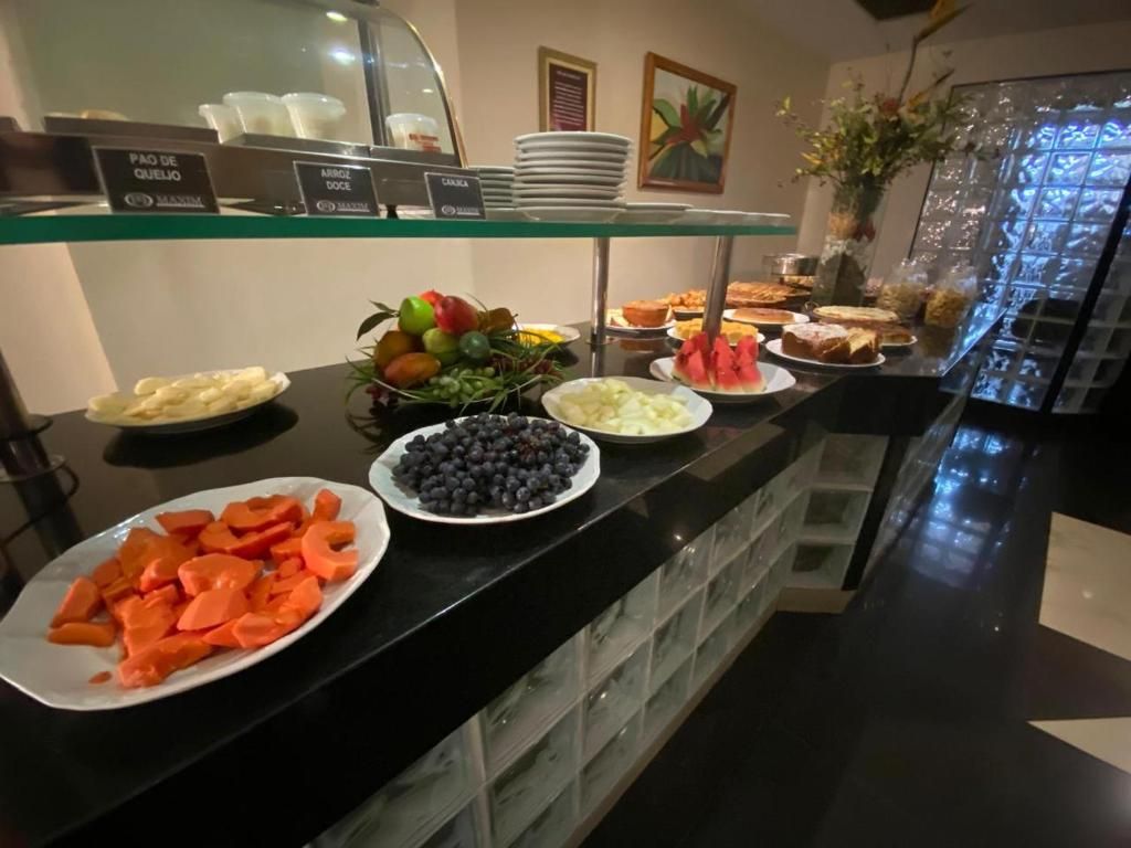 Buffet com diversas opções de comida, incluindo frutas, vegetais e sobremesas.