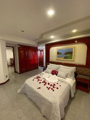 A hotel room with a large bed, a painting on the wall, and a red door. - Maxim Plaza Hotel (Juiz de Fora)