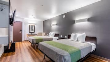 Quarto de hotel com duas camas, uma escrivaninha, um espelho e um guarda-roupa.