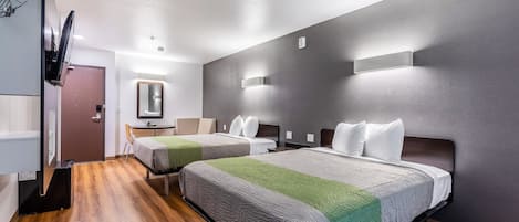 Een hotelkamer met twee bedden, een bureau, een spiegel en een kledingkast.
