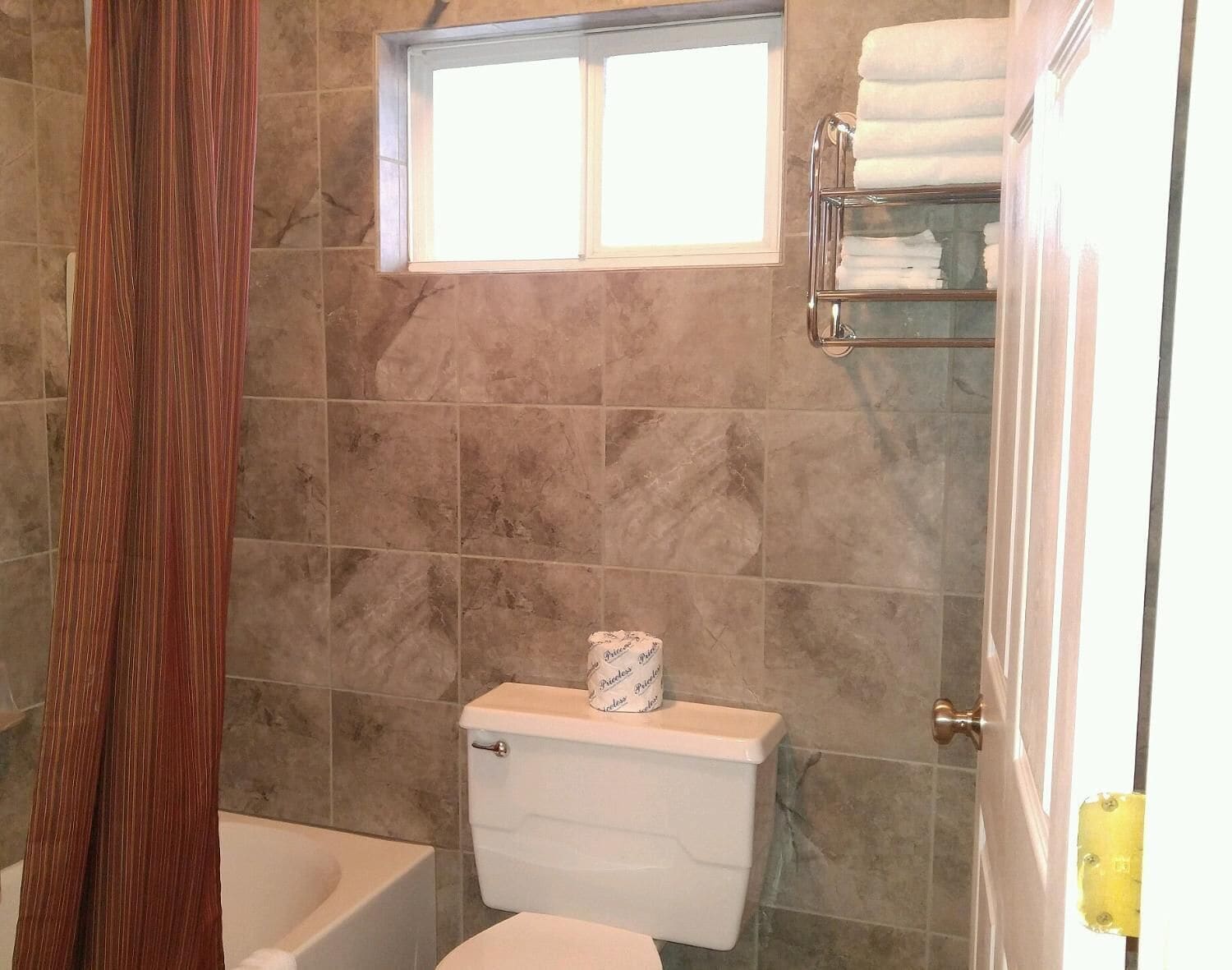 Un baño con inodoro, bañera y cortina de ducha.