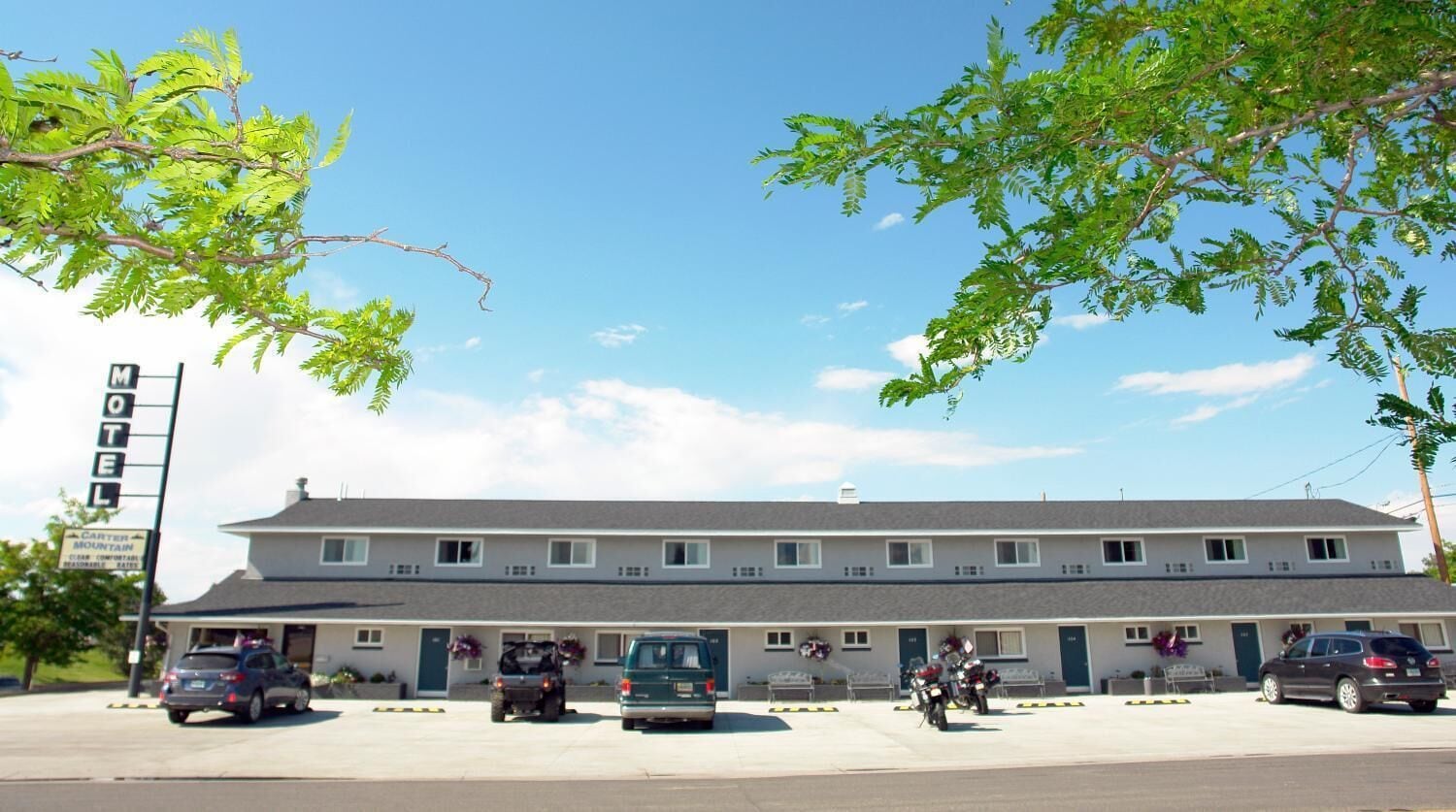 Un motel con varias unidades, un estacionamiento y un letrero que indica un complejo turístico de montaña cercano.