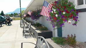 A building with American flags and flower baskets on the exterior wall. - Carter Mountain Motel (Cody)