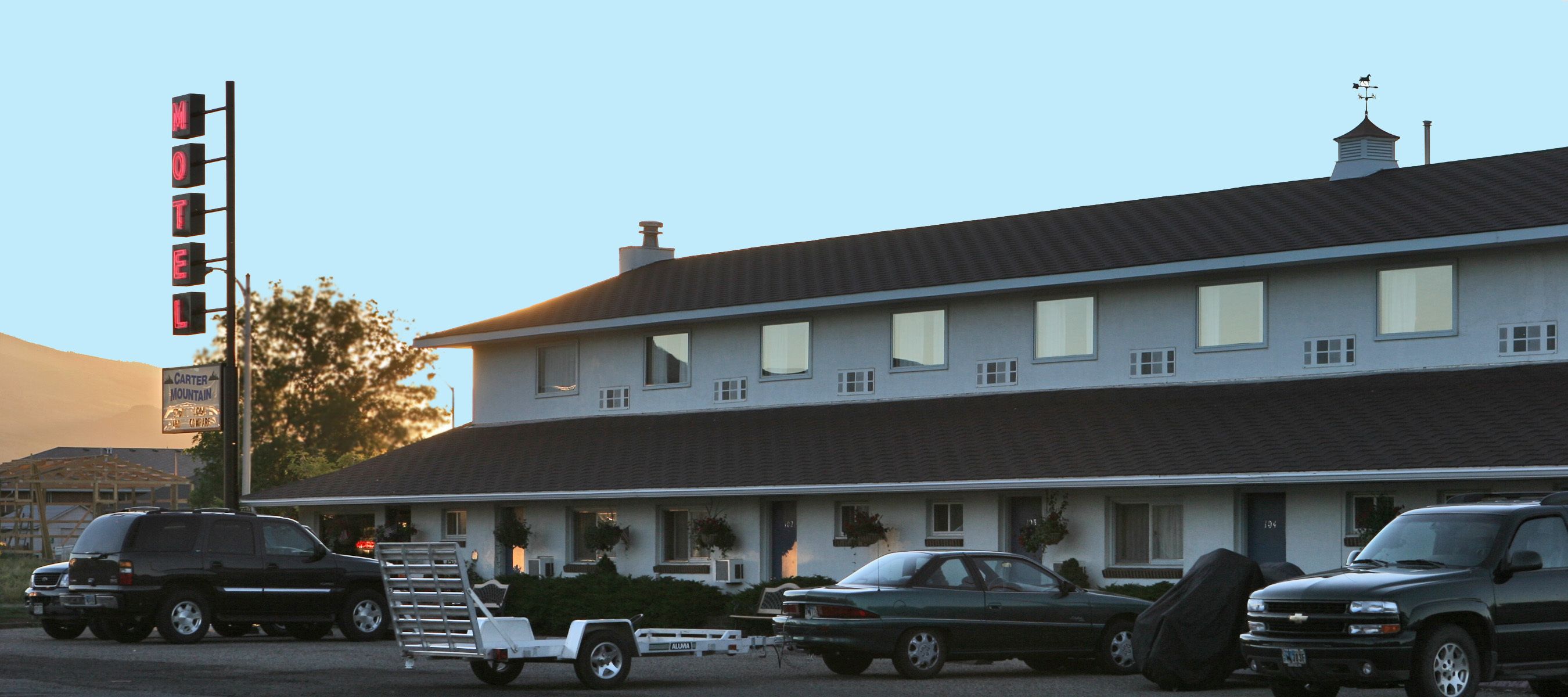 Un motel avec une grande enseigne, de nombreuses fenêtres et un toit plat.
