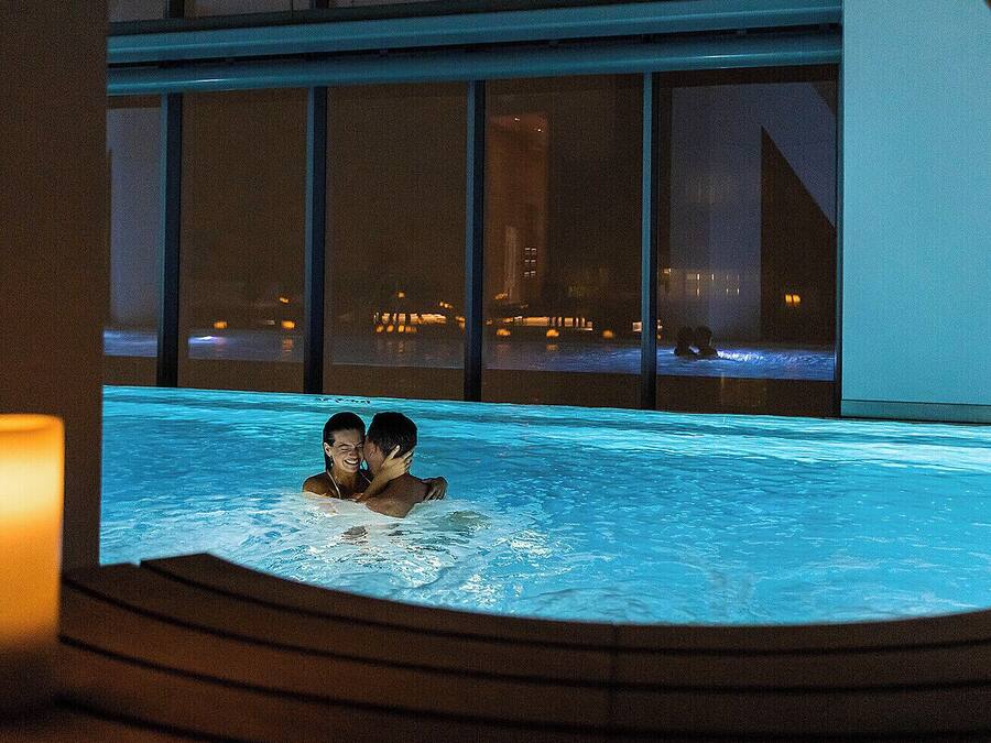 A couple in a hot tub with a city view at night.