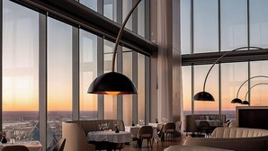 Ein hochgelegenes Restaurant mit weitreichendem Stadtblick, moderner Einrichtung und stilvoller Beleuchtung.
