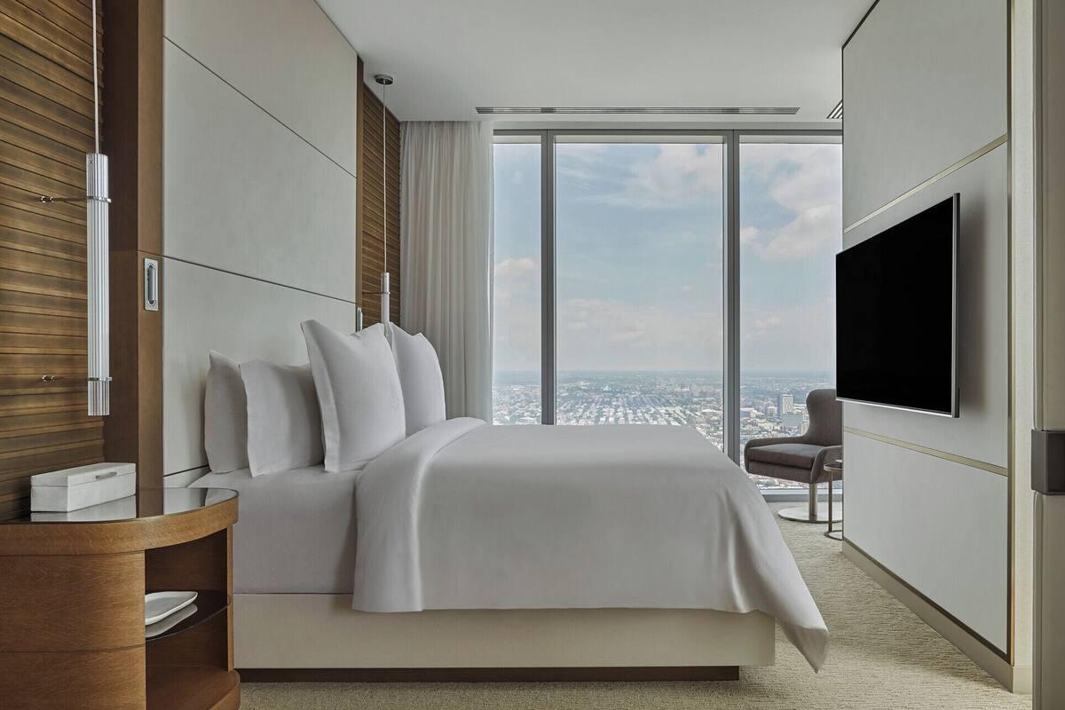 Ein modernes Hotelzimmer mit einem großen Bett, einem Fernseher und Blick auf die Stadt.