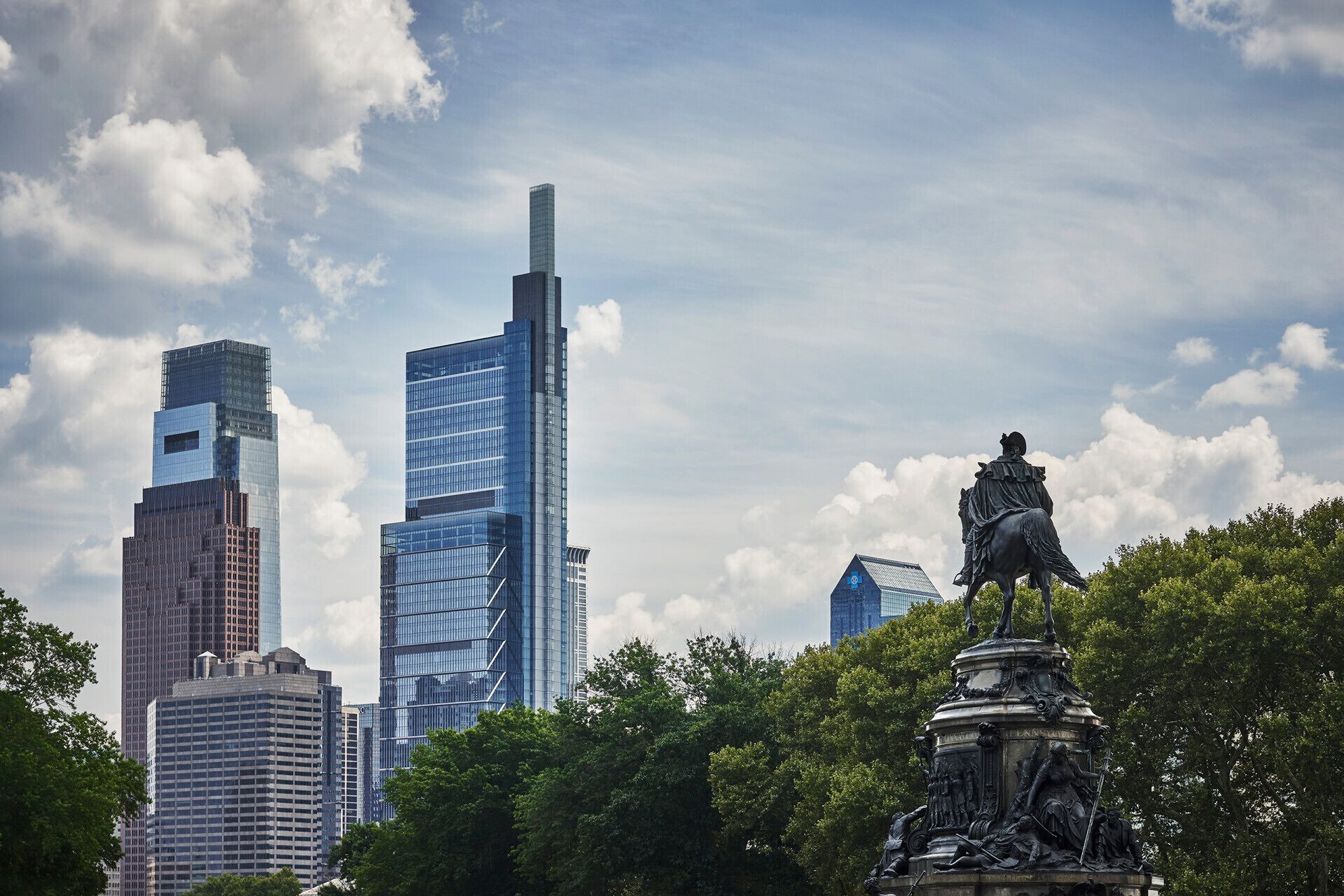 A cityscape with modern skyscrapers and a statue in the foreground.