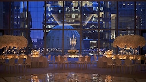 A formal dining area with tables set for six, large windows with a cityscape view, and white floral arrangements on either side. - Four Seasons Hotel Philadelphia at Comcast Center (Philadelphia)