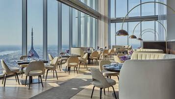 Un comedor moderno con techos altos y ventanas grandes que ofrecen vistas a la ciudad.