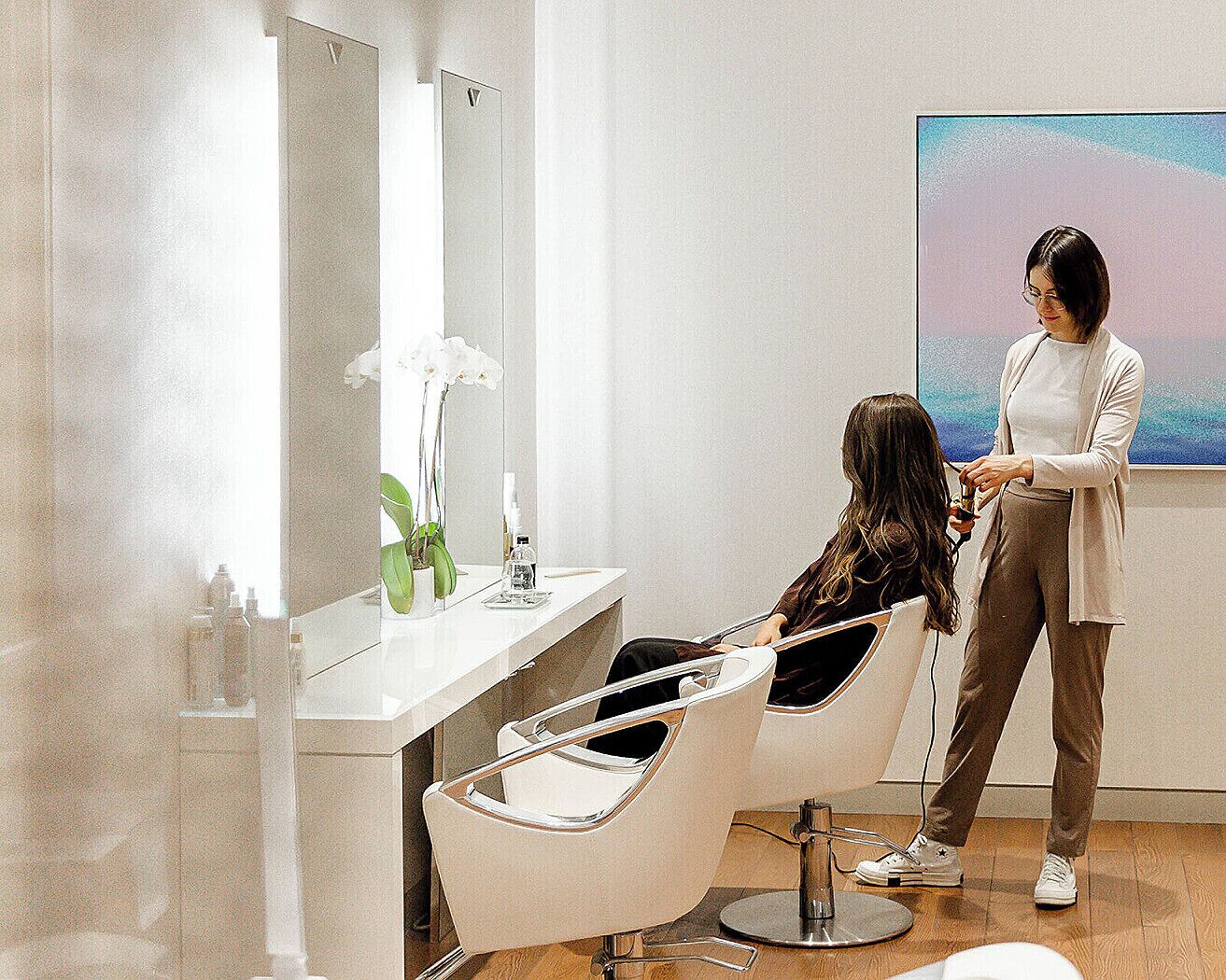 Un salón con una silla moderna, un espejo grande y un cuadro en la pared.