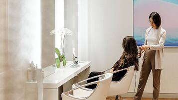 Un salón con una silla moderna, un espejo grande y un cuadro en la pared.