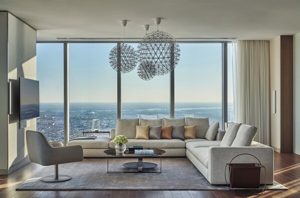 A modern living room with a large window, a sofa, a coffee table, and a TV. - Four Seasons Hotel Philadelphia at Comcast Center (Philadelphia)