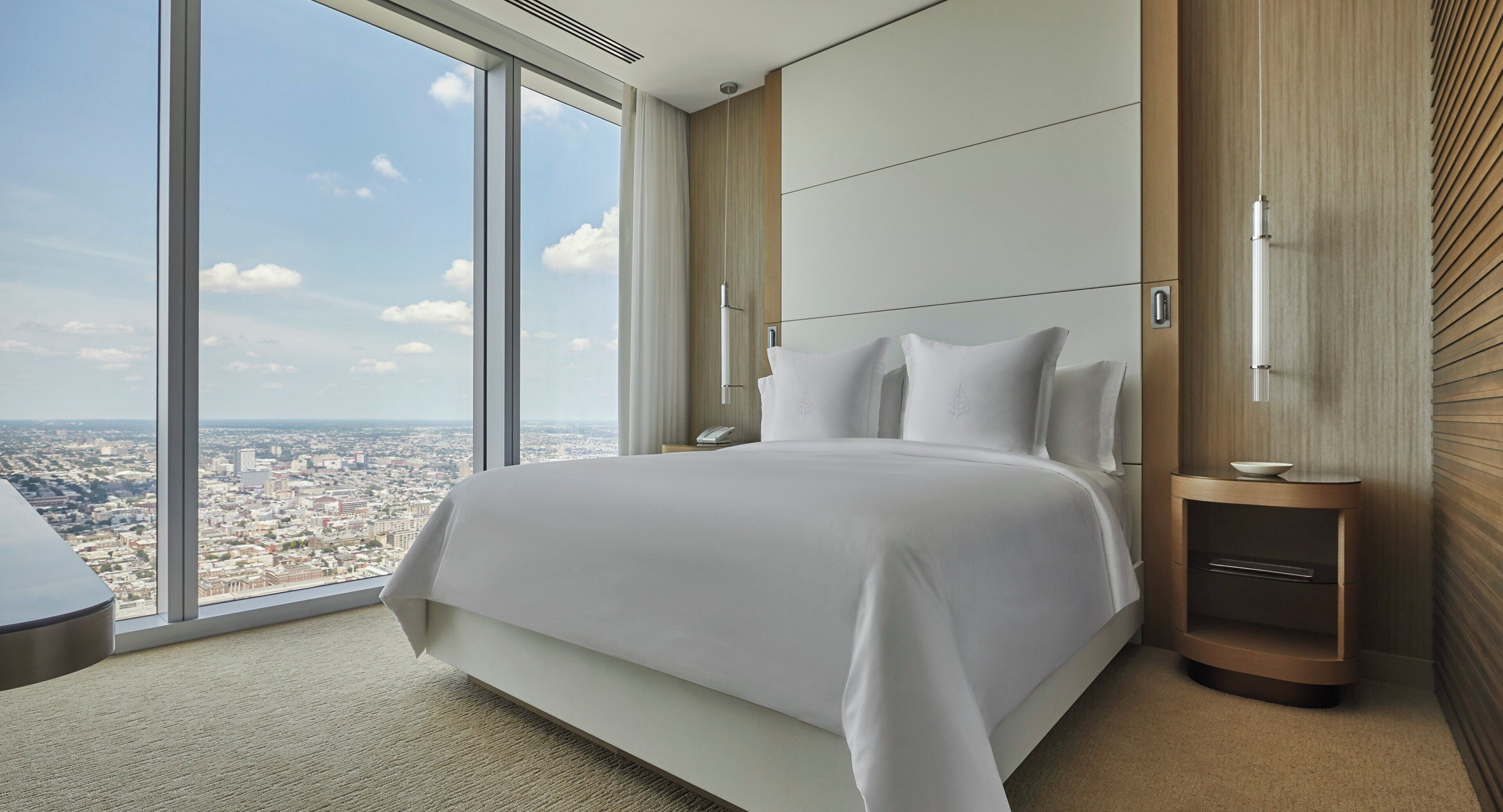 Ein modernes Hotelzimmer mit einem großen Bett, einem Nachttisch und Blick auf die Stadt.