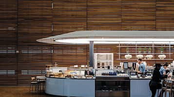 A modern café with a wooden interior, a central counter, and seating areas.
