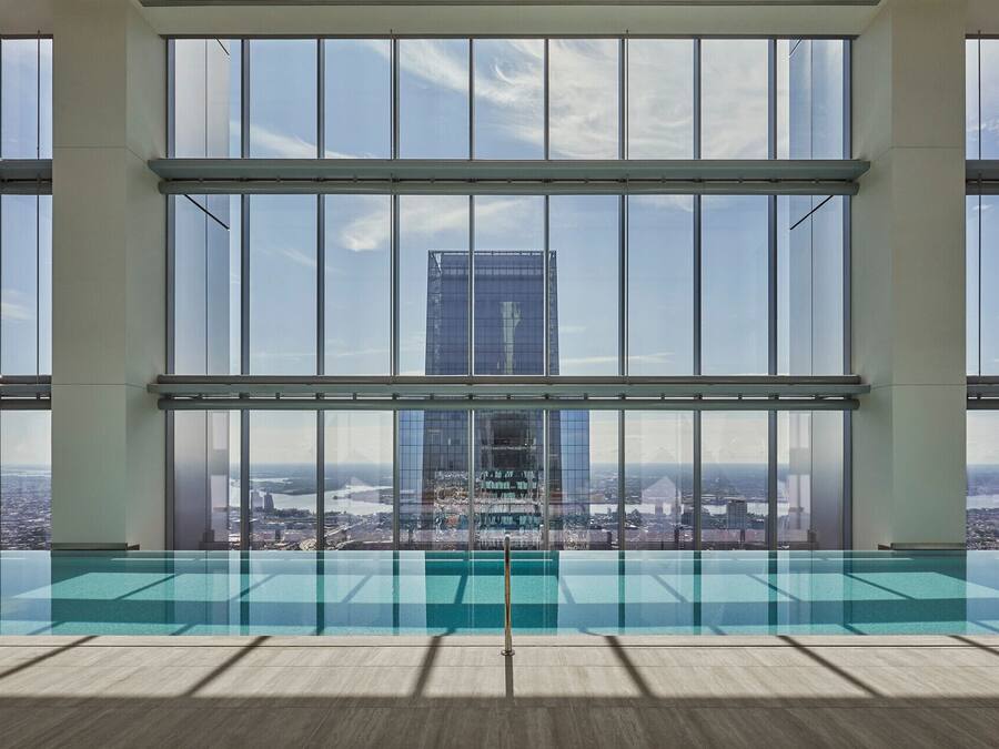 A modern interior with a large glass window overlooking a cityscape and a pool area.