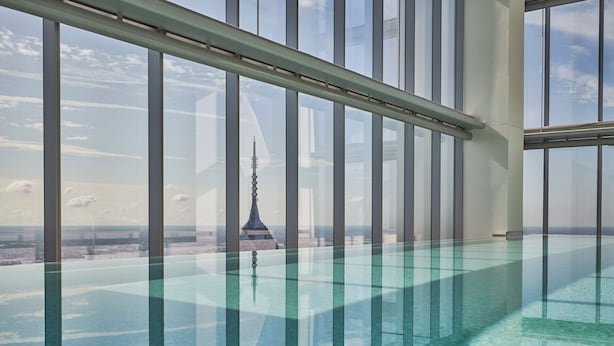Ein moderner Innenpool mit freiem Blick auf einen hohen Turm im Hintergrund.