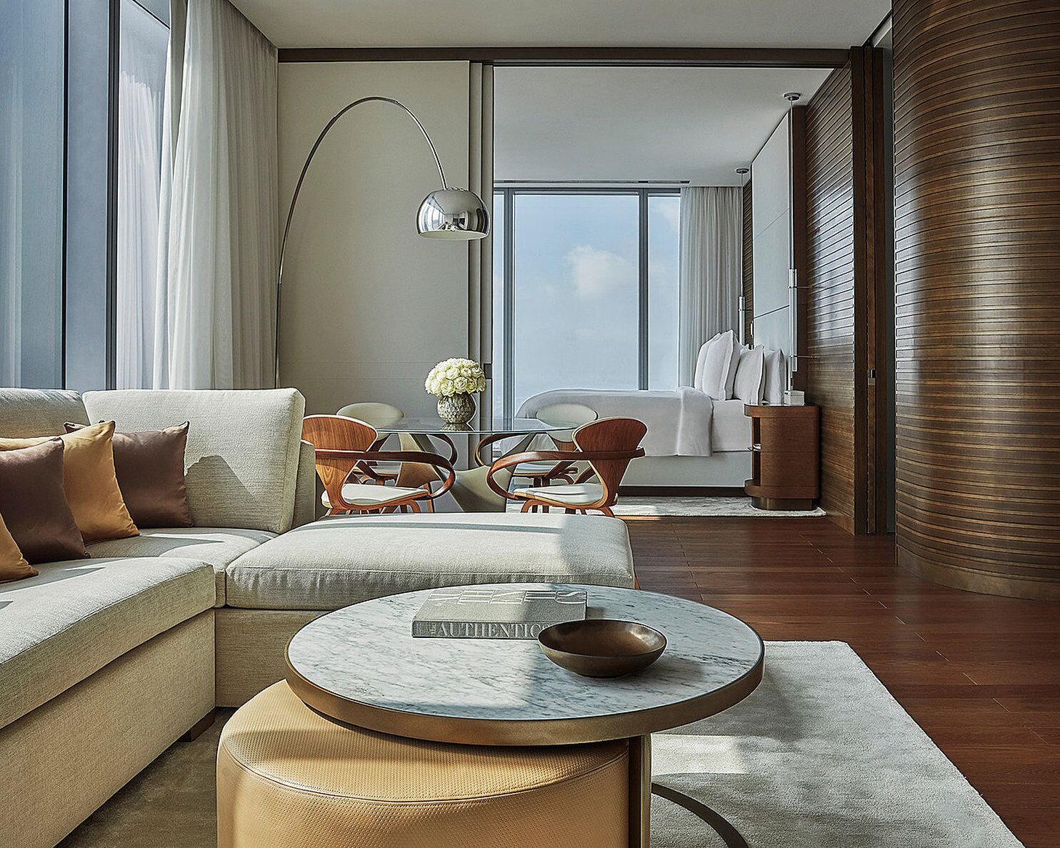 A modern living room with a sectional sofa, a round coffee table, and a dining area with chairs and a table.