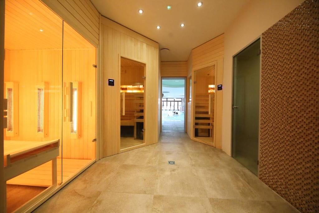 Un pasillo con paredes de madera y piso de baldosas que conduce a una habitación con puerta de vidrio.