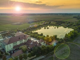 Vista aérea de un hotel con un gran estanque, rodeado de campos y árboles.
