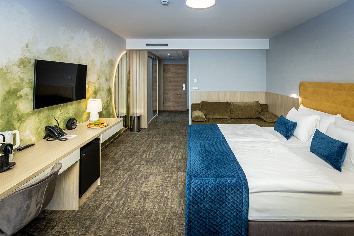Ein Hotelzimmer mit Bett, Schreibtisch mit Computer, Fernseher und Badezimmer.