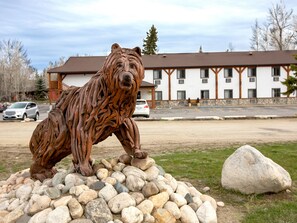 A wooden bear sculpture on a rock formation with a building in the background. - Beartooth Hideaway Inn and Cabins (Red Lodge)