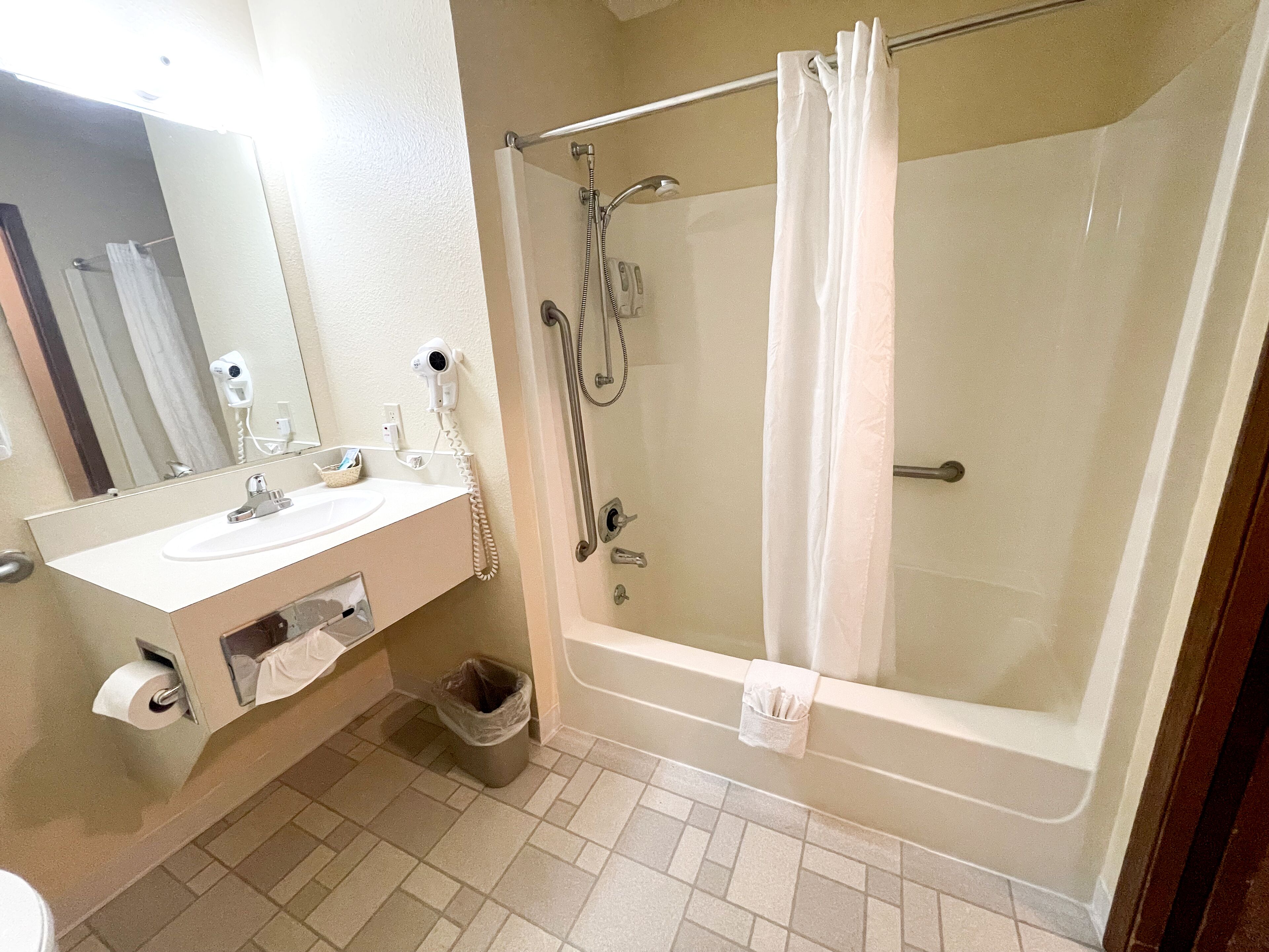 Bagno con lavandino, specchio, asciugacapelli, doccia e WC.