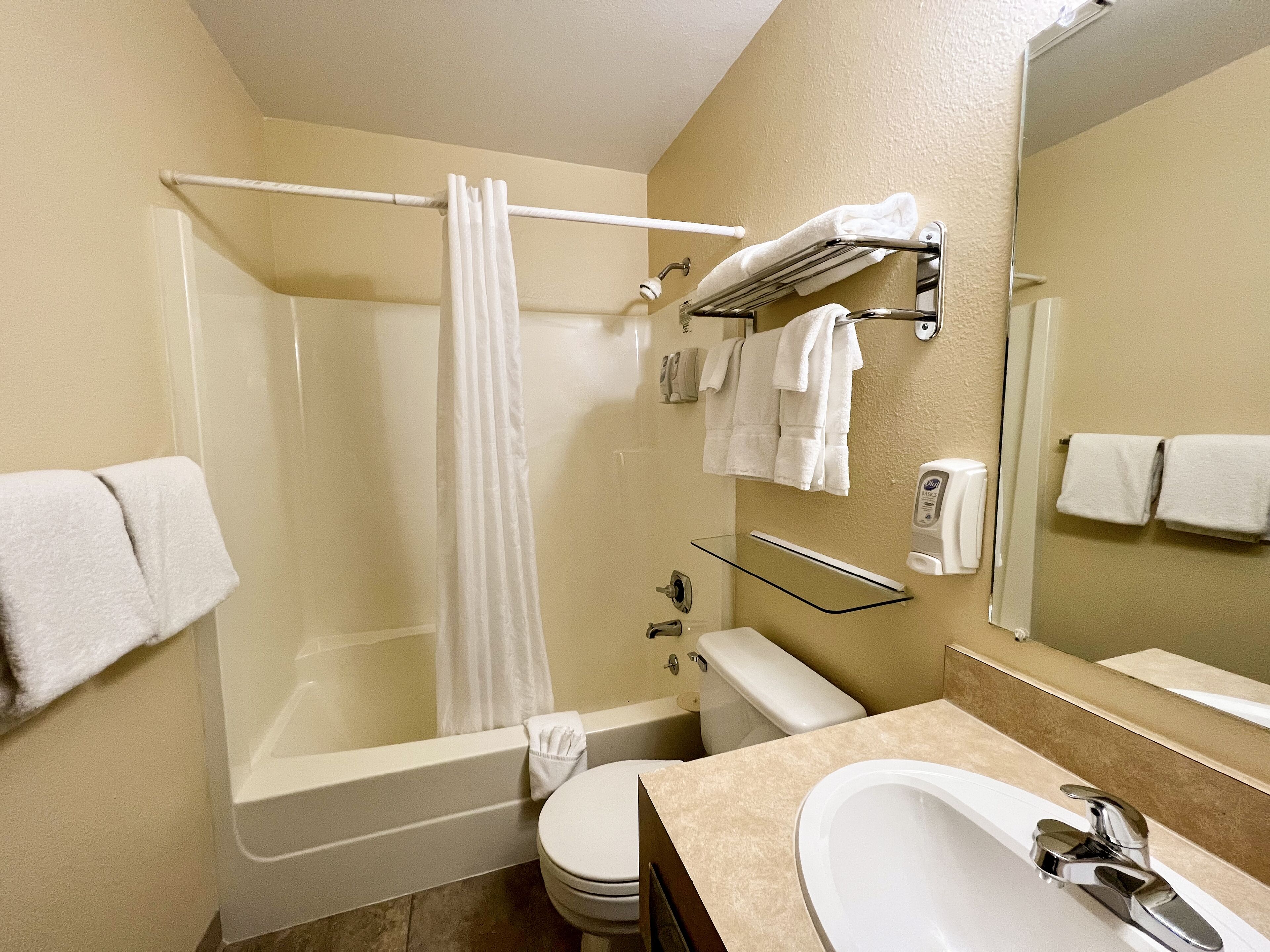 Un bagno moderno con cabina doccia in vetro, vasca, water e lavabo con rubinetteria cromata.