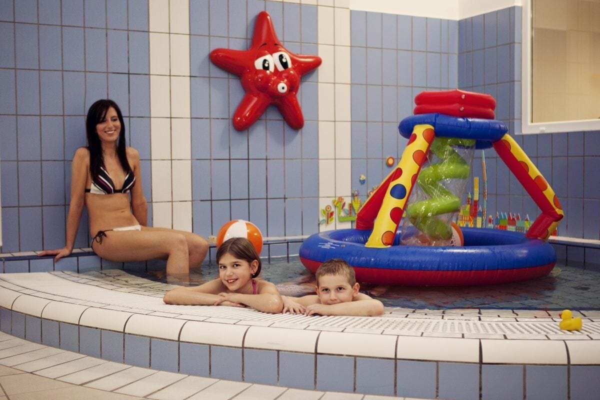 A swimming pool area with a starfish decoration, a children's inflatable play structure, and tiled walls.