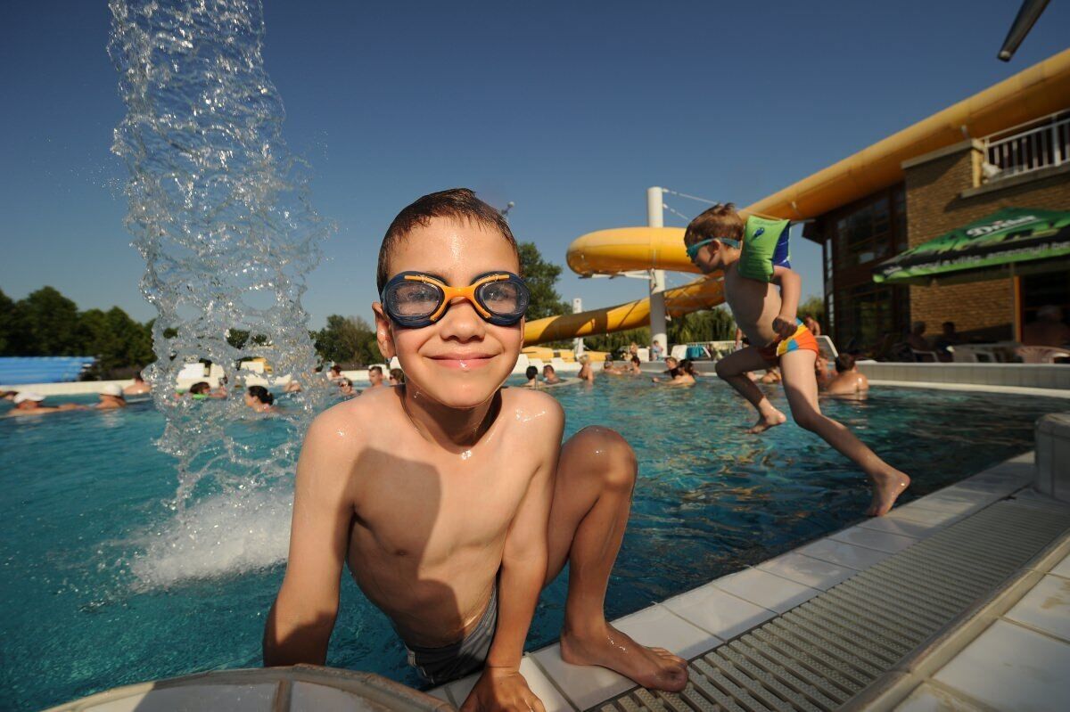 Una piscina con uno scivolo acquatico e persone che nuotano.