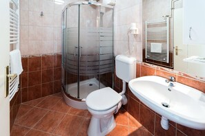 A bathroom with a glass-enclosed shower, a white toilet, and a sink. - Hotel Napfény (Zalakaros)