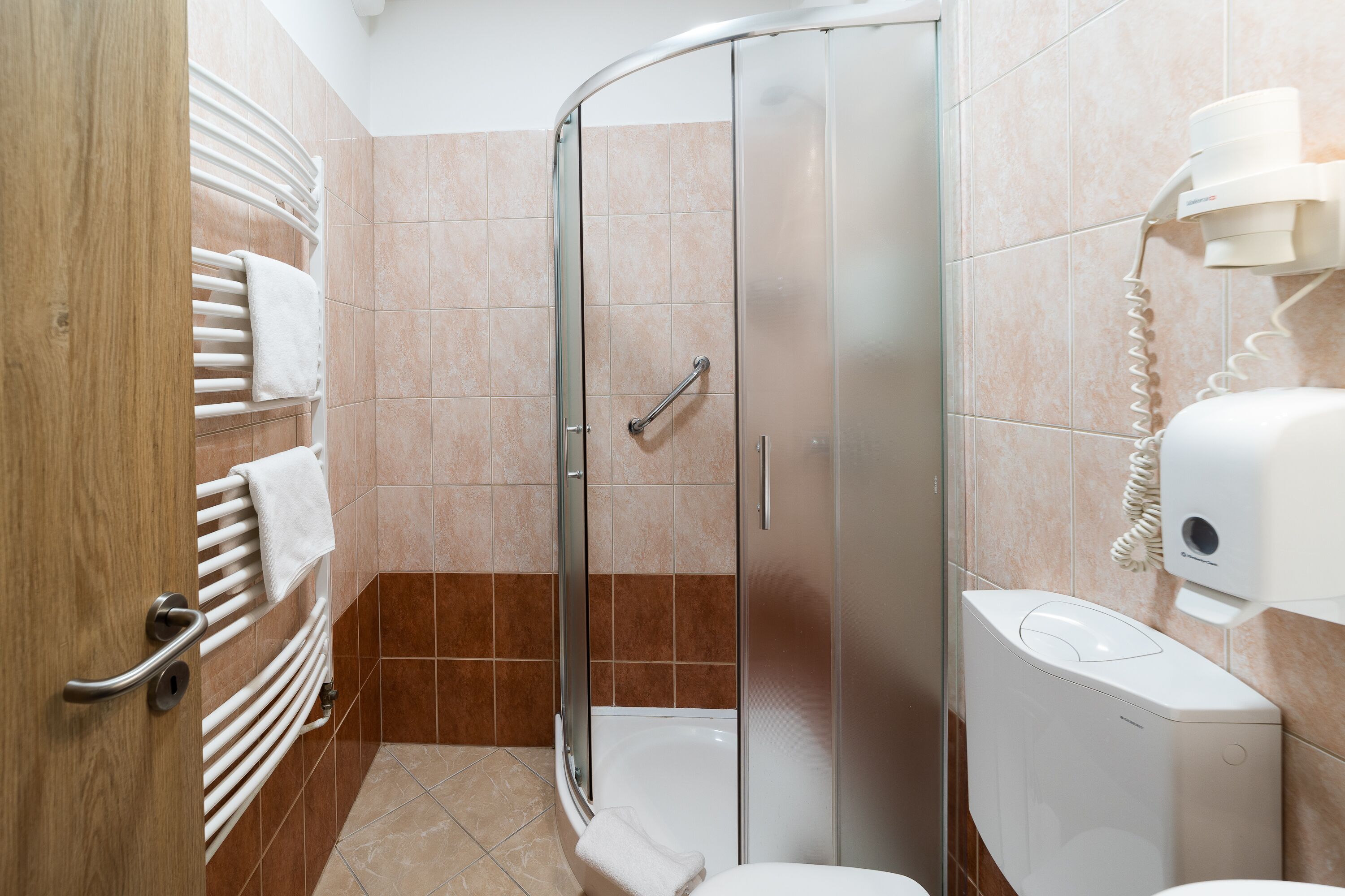 Un baño moderno con cabina de ducha de vidrio, inodoro y barra para toallas.