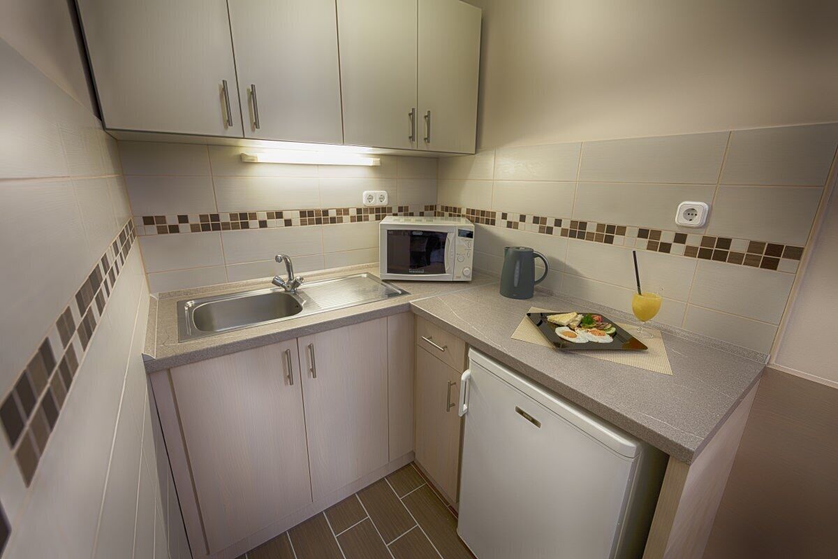 Cocina compacta con microondas, lavamanos y un refrigerador pequeño.