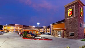 Un hotel Super 8 con estacionamiento, varias edificaciones y una fachada bien iluminada.