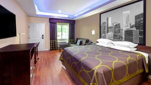 Habitación de hotel con una cama grande, un escritorio, una silla, una ventana con cortinas y un mural de un paisaje urbano en la pared.