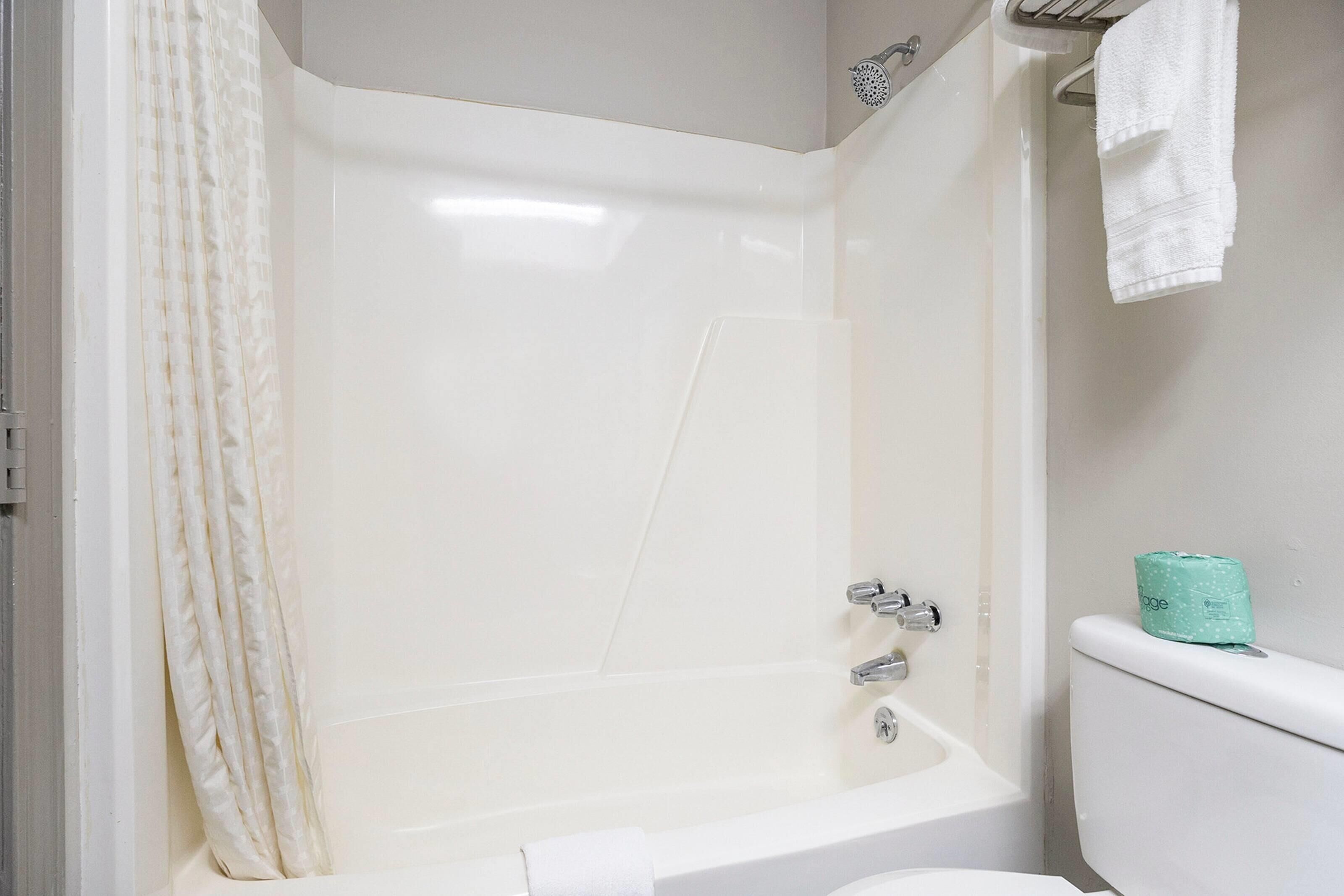 A bathroom with a bathtub, toilet, and shower curtain.