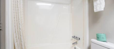 A bathroom with a bathtub, toilet, and shower curtain.