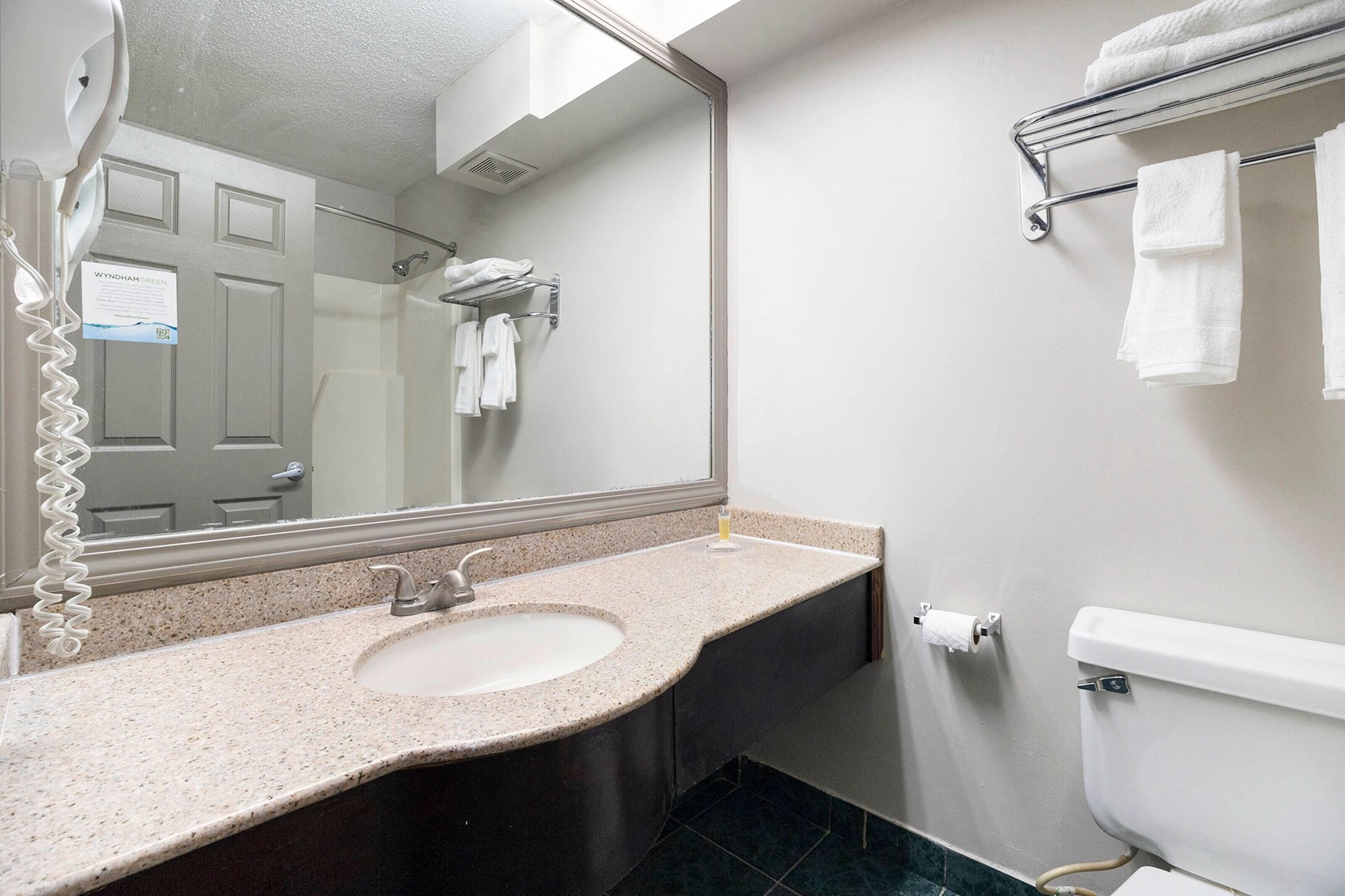 A bathroom with a sink, mirror, towel rack, and toilet.